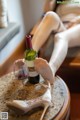 A woman sitting on a table with a glass of wine and a pair of shoes.