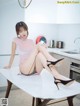 A woman sitting on top of a table in a kitchen.