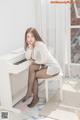 A woman sitting on top of a white piano.