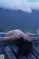 A woman laying on top of a roof with mountains in the background.