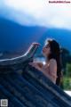 A woman in a pink bikini leaning on a roof.