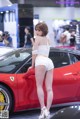 A woman standing next to a red sports car.