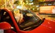 A woman sitting in the driver's seat of a red car.