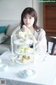 A woman sitting at a table with three tiered trays of food.