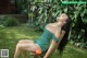 A woman in a green dress sitting on a wooden chair.