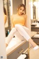 A woman sitting on top of a counter in front of a mirror.