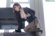 A woman in a black dress sitting on top of a dresser.