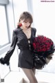 A woman in a black dress holding a bouquet of red roses.