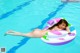 A naked woman laying on an inflatable ring in a swimming pool.