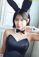 A woman in a black dress with bunny ears and a bow tie.