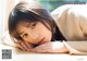 A young woman laying on a wooden table with her hand on her chin.