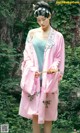 a woman in a pink kimono standing in front of a tree