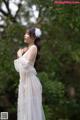 A woman in a white dress standing in the woods.