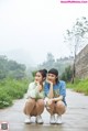 Two young women sitting on the side of a road.