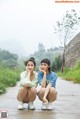 Two young women sitting on the side of a road.