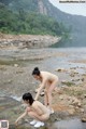 A couple of women standing next to each other near a river.