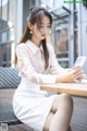 A woman sitting at a table looking at her phone.