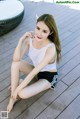 A woman sitting on a wooden floor next to a pool.