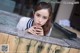 A woman leaning over a wooden fence with her hand on her chin.