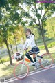 A woman riding a bike with a basket full of flowers.