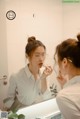 A woman applying lipstick in front of a mirror.