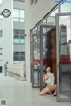 A woman sitting on the ground in front of a glass door.