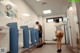 A woman standing in a public restroom next to a man.