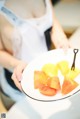 A woman holding a plate with sliced fruit on it.