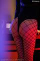 A woman in fishnet stockings is sitting on a table.