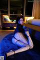 A woman in fishnet stockings sitting on a blue rug.