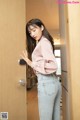 a woman in jeans and a pink shirt is opening a door