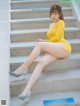 A woman in a yellow dress sitting on some steps.