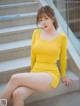 A woman in a yellow dress sitting on some steps.