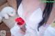 A woman in a white dress holding a bouquet of red roses.