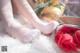 A woman sitting on top of a white rug next to a bouquet of roses.