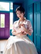 A woman in a white dress sitting on a blue door.