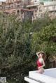 A woman in a red bathing suit standing on a balcony.