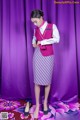 A woman in a purple and white striped skirt and a pink vest.