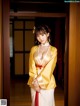 A woman in a yellow and white kimono posing for a picture.