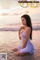 A woman in a white dress sitting in the water.