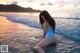 A woman in a blue bathing suit sitting in the ocean.