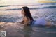 A woman laying in the water at the beach.