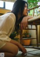 A woman sitting on the floor next to a wooden chair.