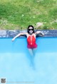 A woman in a red bathing suit is floating in a pool.