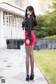 A woman in a black shirt and red skirt posing for a picture.