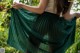 A woman in a green pleated skirt is standing in the grass.