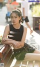 A woman sitting on top of a wooden bench.