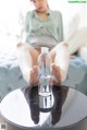 A woman sitting on a couch with her feet up next to a bottle of water.