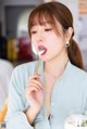 A woman eating a piece of food with a spoon.