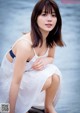 A woman in a white dress sitting on the water.